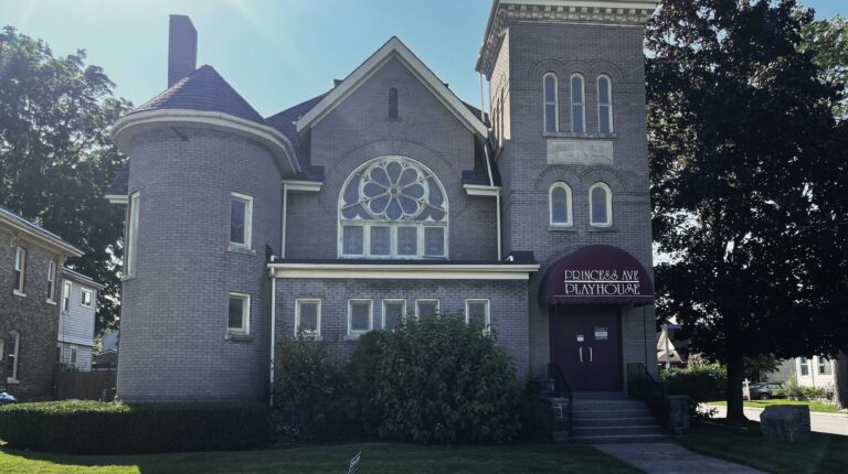 The Princess Avenue Playhouse in St. Thomas, home of the Elgin Theatre Guild: a two-towered former brick church with a rose window and a burgundy Princess Ave Playhouse awning over the entrance, its tower stone reading Church of Christ A.D. 1906.