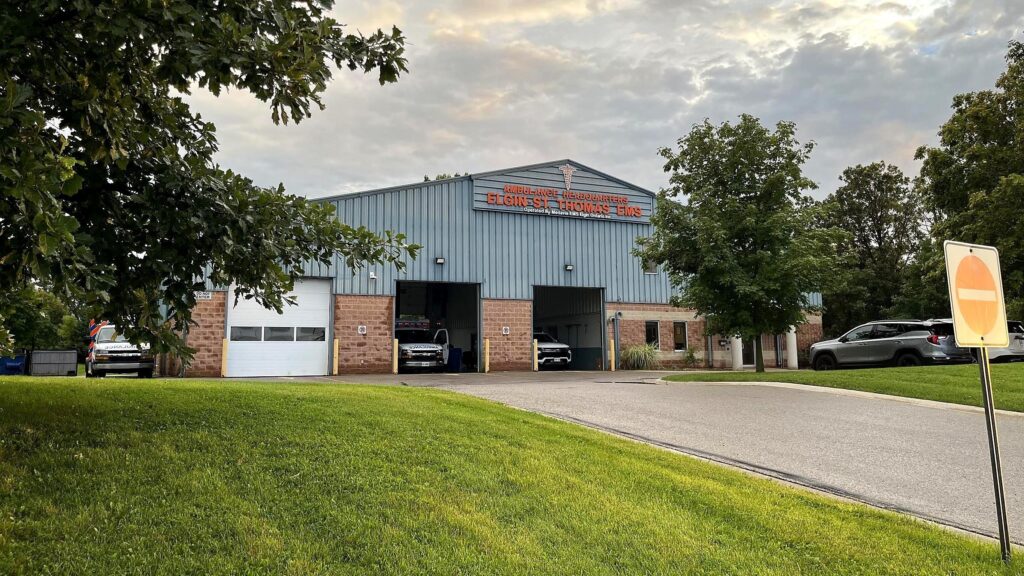 The Elgin-St. Thomas EMS ambulance headquarters on Edward Street in St. Thomas, a blue steel building with two open bays and ambulances inside, operated by Medavie EMS Elgin Ontario Inc.